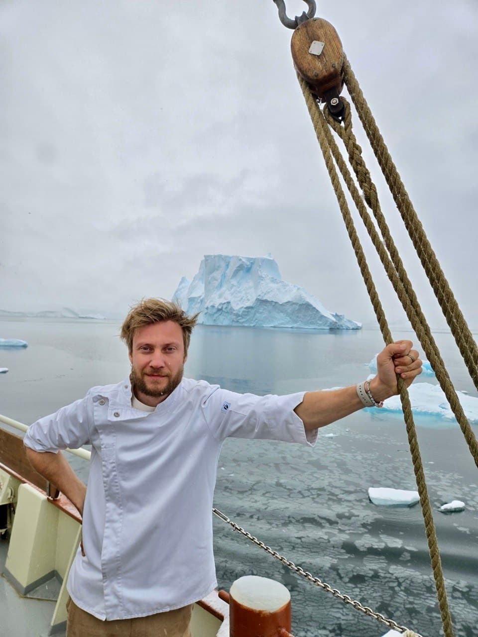 Chef de MUSGO en la cubierta del velero, con un témpano al fondo